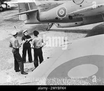 US-FLUGZEUGE FÜR DIE BRITISCHE FLOTTENFLOTTE. OKTOBER 1943 IN DEN VEREINIGTEN STAATEN. DIE FLOTTENFLOTTE DER ROYAL NAVY SETZT DIE NEUESTEN FLUGZEUGTYPEN EIN, DIE IN DEN USA GEBAUT WURDEN. EINIGE DER FLUGZEUGE, DIE SICH IN DER PRÜFUNG, VERPACKUNG UND VERSAND AUS DEN USA BEFINDEN. - Royal Navy und Wren Checker arbeiten an Flugzeugen der Royal Navy. , Stockfoto