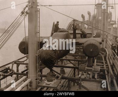 US-ARMEE-LUFTSTREITKRÄFTE (USAAF) IN GROSSBRITANNIEN, 1942-1945 - US-Angehörige entladen eine gewickelte P-61 Black Widow am Liverpool Docks. Bild auf der Rückseite: 'Associated Press'. [Stempel], 'nicht zu veröffentlichen [kein Datum].' [Stempel], „Bestanden & zensiert 1. April 1944.“ [Stempel], 'zur Veröffentlichung am 4. Juni 1945 bestanden.' [Stempel], „314297“. [Censor no].gedruckte Beschriftung auf der Rückseite: 'Die 'Black Widow' kommt in EnglandAssociated Press Photo zeigt: 'Black Widows' an Bord des Schiffes, das sie sicher von den USA in dieses Land brachte, bereit zum Entladen.' handgeschriebene Beschriftung auf der Rückseite: '266416'. , Stockfoto