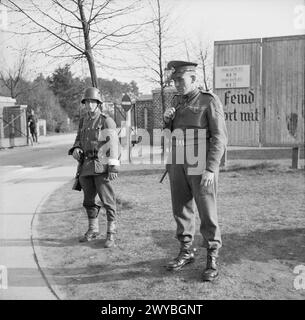 Im April 1945 stehen ein britischer Militärpolizist und ein ungarischer Soldat vor dem Konzentrationslager Bergen-Belsen Wache. Ungarische Truppen blieben unter dem Waffenstillstand und erfüllten Arbeitsaufgaben. Stockfoto