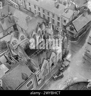 COVENTRY, FRÜHJAHR 1944: ALLTAGSLEBEN IN COVENTRY, WARWICKSHIRE, ENGLAND, Großbritannien, 1944 - die dachlose Hülle der St. Michael's Baptist Church in Coventry, die von der Spitze des Westturms der Kathedrale stammt. In der oberen rechten Ecke des Fotos ist ein jakobinischer Pub mit Fachwerk „das Goldene Kreuz“ zu sehen, der den Blitz unbeschadet überlebte. , Stockfoto