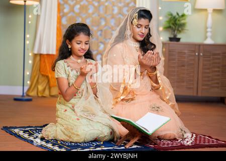 Indische muslimische Frau mit Tochter betend Gott durch Namen während des Ramadan feastiva zu Hause - Konzept der Freilassung, Bindung und Feier. Stockfoto