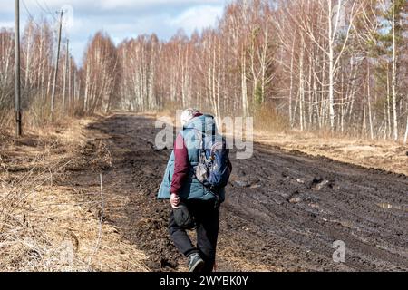 Frühlingslandschaft mit schlammigen Sümpfen, Waldstraße, Frühling, einsamer Reisende auf einer schmutzigen nassen Straße, Frühling Stockfoto