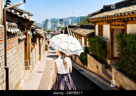 Südkorea, Seoul. Frau in Hanbok im Dorf Bukchon Hanok. Mädchen in traditionellem Kleid und Kostüm. Koreanische Tradition. Skyline der Stadt. Stockfoto