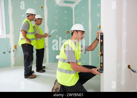 Arbeiter mit Schutzausrüstung, PSA, Nivellieren von Gipskartonplatten, Gehäusebau, Ebene, Baskenland, Spanien. Stockfoto