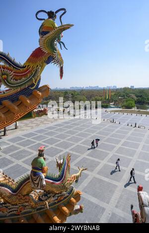 Majestätische Drachenstatue auf einem Tempel mit herrlichem Blick auf die Stadtlandschaft und die Menschen, die darunter laufen Stockfoto