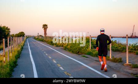Ein Mann, der bei Sonnenaufgang auf einem Joggingpfad in Marina del Rey, Kalifornien, USA läuft. Gesunde Gewohnheiten, Laufen für Fitness, Bewegung am Morgen Stockfoto