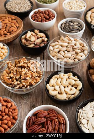 Rohe Walnüsse und Cashew mit Mandeln und Erdnüssen mit Bio-Nüssen und Samen in verschiedenen Schüsseln. Stockfoto