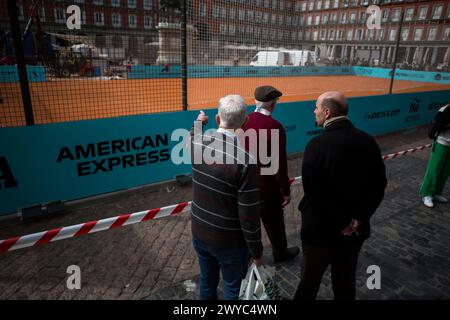 Madrid, Spanien. April 2024. Drei ältere Menschen beobachten einen Tennisplatz auf der Plaza Mayor von Madrid. Auf dem Plaza Mayor in Madrid wird ein Tennisplatz eingerichtet, um das Turnier Mutua Madrid Open 2024 zu fördern, an dem die besten Tennisspieler der Welt teilnehmen, das vom 22. April bis 5. Mai in Madrid im Caja Magica stattfindet. Quelle: SOPA Images Limited/Alamy Live News Stockfoto