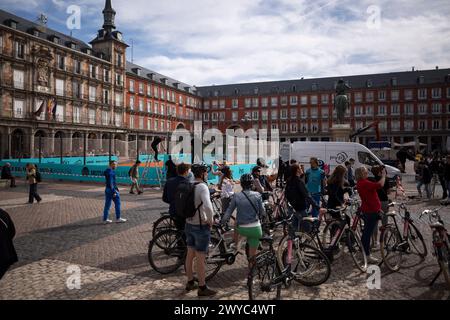 Madrid, Spanien. April 2024. Blick auf Touristen auf Fahrräder und Hintergrund eines Tennisplatzes auf der Plaza Mayor von Madrid. Auf dem Plaza Mayor in Madrid wird ein Tennisplatz eingerichtet, um das Turnier Mutua Madrid Open 2024 zu fördern, an dem die besten Tennisspieler der Welt teilnehmen, das vom 22. April bis 5. Mai in Madrid im Caja Magica stattfindet. Quelle: SOPA Images Limited/Alamy Live News Stockfoto