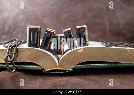 Die Wahrheit wird dich befreien, Stillleben-Konzept mit goldenem Buch und gebrochenen Ketten, weichem Fokus Stockfoto