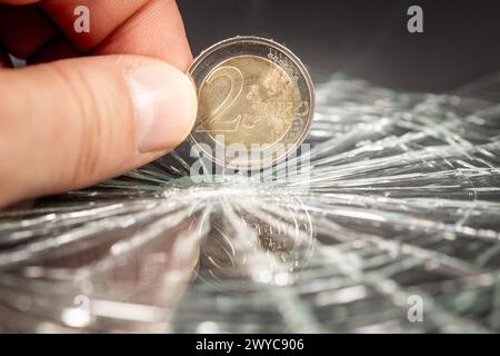 Europäisches Geld, 2-Euro-Münze, die sich in Glasscherben widerspiegelt, Finanzkonzept, europäische Währung, Kursrückgang, Analyse und Prognosen für die Eurozone Stockfoto