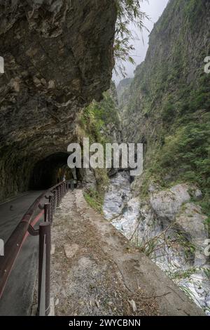 Ein dramatischer Blick auf die enge Taroko-Schlucht mit steilen Klippen, einem fließenden Fluss und einer abgeschiedenen Straße Stockfoto