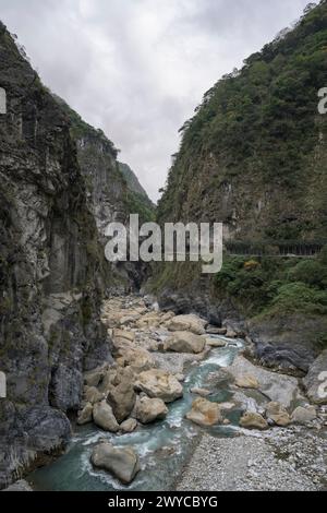 Ein dramatischer Blick auf die enge Taroko-Schlucht mit steilen Klippen, einem fließenden Fluss und einer abgeschiedenen Straße Stockfoto