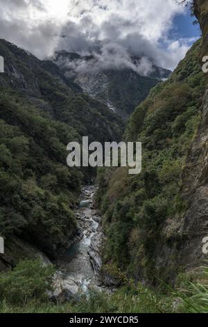 Ein dramatischer Blick auf die enge Taroko-Schlucht mit steilen Klippen, einem fließenden Fluss und einer abgeschiedenen Straße Stockfoto