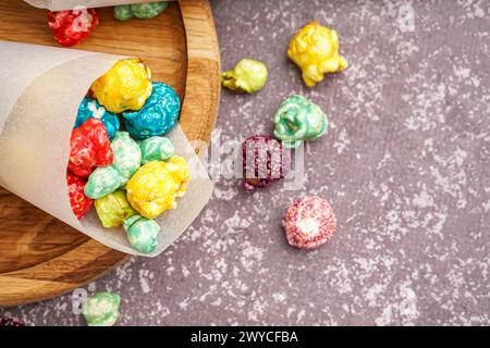 Papierkegel mit süßem bunten Popcorn auf dunklem Hintergrund Stockfoto