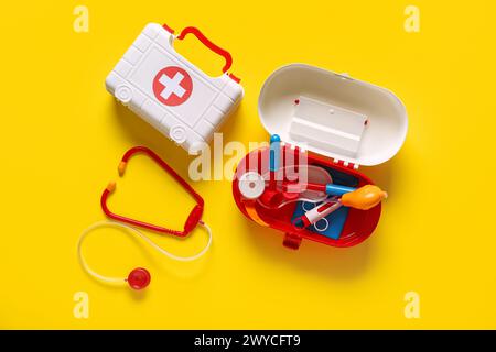 Erste-Hilfe-Sets für Spielzeug mit Stethoskop auf gelbem Hintergrund. Draufsicht Stockfoto