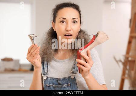 Schockierte Schuhmacherin mit gebrochener Ferse in der Werkstatt Stockfoto