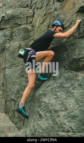 Junger Mann in Ausrüstung, der draußen klettert. Trainingsbereich für Outdoor-Aktivitäten. Extremsport. Stockfoto