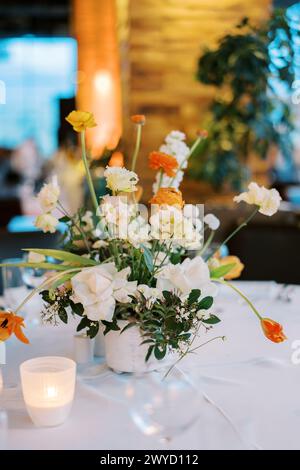 Heller Blumenstrauß in einer Vase steht auf einem gedeckten Tisch Stockfoto