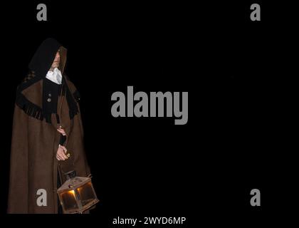 EN la Procesión nocturna de las CAPAs Pardas de Zamora, un cofrade avanza con paso firme y reverente por las estrechas calles. Zamora, España Stockfoto