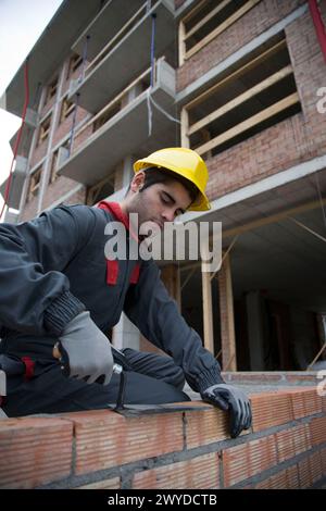 Arbeiter, der Ziegelwände mit Kelle herstellt. Hochbau. Stockfoto