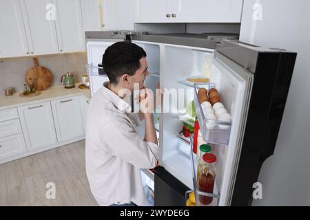 Aufmerksamer Mann in der Nähe des Kühlschranks in der Küche zu Hause Stockfoto