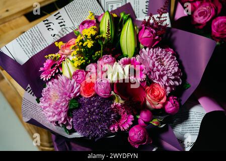 Ein exquisiter Blumenstrauß, einschließlich Rosen und Gerberas, verpackt in einer kreativen Zeitungspapier, ideal zum Schenken. Stockfoto