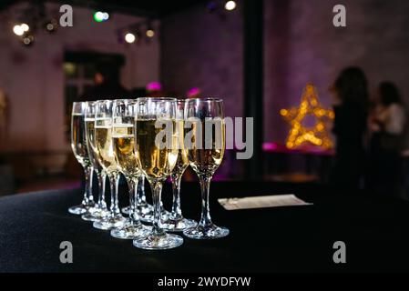 Champagner zum Anstoßen bereit für die Feier. Auf einer dunklen Tischdecke stehen Gläser Sekt, die bei einer festlichen Veranstaltung auf die Gäste warten Stockfoto