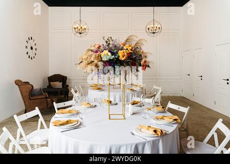 Ein eleganter Esstisch mit goldenen Akzenten und einem üppigen, floralen Herzstück in eleganter Inneneinrichtung. Stockfoto