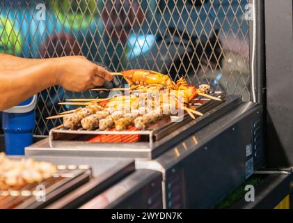 Gegrillte Tintenfische mit Stock auf einem Straßenmarkt. Stockfoto