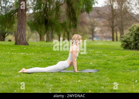 Frau macht Yoga im Park, Kobra-Bewegung. Stockfoto