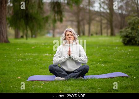Frau, die im Lotus sitzt und im Freien meditiert. Stockfoto