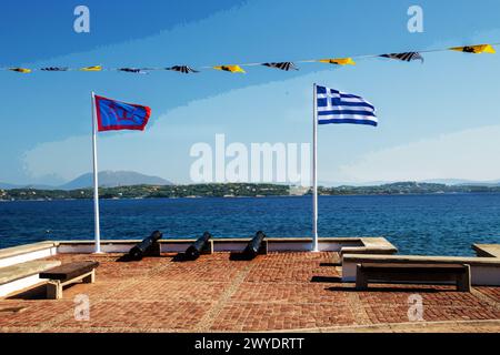 Die Flaggen Griechenlands und vielleicht die Insel Spetses. Auf dem anderen Kanal - Festland von Griechenland. Fantastische Sommererholung auf griechischen Inseln, auch Kreta, Rhodos, S Stockfoto