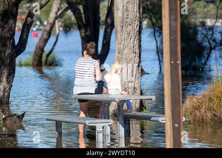 Samstag, 6. April 2024. Sydney wurde in den letzten 48 Stunden von einer Regenflut heimgesucht, wobei einige Gebiete, darunter Penrith, die stärksten Regenfälle aller Zeiten hatten. In Narrabeen wurden Bewohner um die Narabeen Lagune gebeten, wegen des steigenden Wasserspiegels vom Narrabeen Lake an den nördlichen Stränden von Sydney zu evakuieren. wo über 150 mm Regen gefallen sind. In New South Wales gab es mehr als 50 Hochwasserwachen entlang der Flüsse und es wird erwartet, dass der Warragamba-Damm ausläuft. Mutter und Kind sitzen auf untergetauchten Parkbank und Tisch. Credit Martin Berry @alamy Live News. Stockfoto