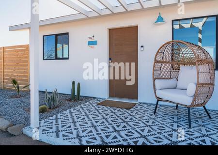 Moderne Bohème Wüstenhaus Veranda mit Fliesen und Rattanstuhl tagsüber Stockfoto