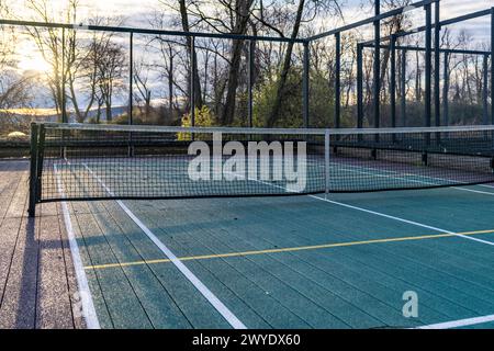 Elevated Platform Tennis, Paddle Ball Courts mit gelben Pickelballlinien, Netz und Hühnerdrahtzaun. Die Bodenfläche ist grün, kastanienbraun, weiß und Stockfoto