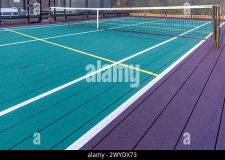 Elevated Platform Tennis, Paddle Ball Courts mit gelben Pickelballlinien, Netz und Hühnerdrahtzaun. Die Bodenfläche ist grün, kastanienbraun, weiß und Stockfoto