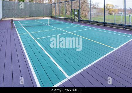 Elevated Platform Tennis, Paddle Ball Courts mit gelben Pickelballlinien, Netz und Hühnerdrahtzaun. Die Bodenfläche ist grün, kastanienbraun, weiß und Stockfoto