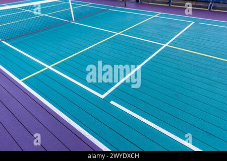 Elevated Platform Tennis, Paddle Ball Courts mit gelben Pickelballlinien, Netz und Hühnerdrahtzaun. Die Bodenfläche ist grün, kastanienbraun, weiß und Stockfoto