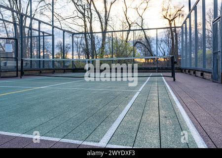 Elevated Platform Tennis, Paddle Ball Courts mit gelben Pickelballlinien, Netz und Hühnerdrahtzaun. Die Bodenfläche ist grün, kastanienbraun, weiß und Stockfoto