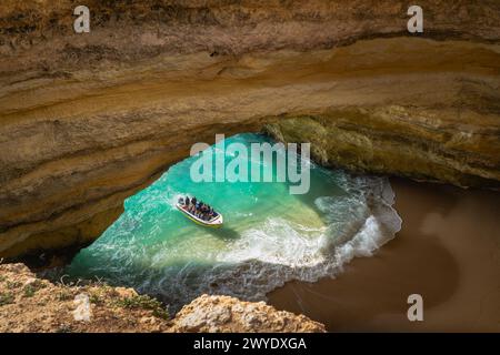 Touristen in einem Boot erkunden das türkisfarbene Wasser in der Benagil-Höhle in der Algarve, Portugal. Stockfoto