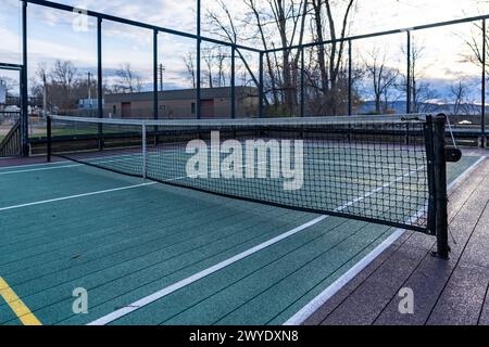 Elevated Platform Tennis, Paddle Ball Courts mit gelben Pickelballlinien, Netz und Hühnerdrahtzaun. Die Bodenfläche ist grün, kastanienbraun, weiß und Stockfoto