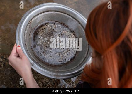 Rothaarige Frau sucht mit einer Eisenpfanne nach Gold. Goldwaschen in Sovereign Hill, Ballarat, Australien Stockfoto