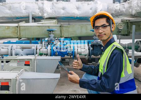 Junger Ingenieur, männlich in reflektierender Weste, gibt einen Daumen nach oben, um die Leitung zu überprüfen. Gasleitung in gutem Zustand Stockfoto