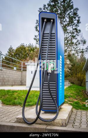 Öffentliches Autoladegerät an der Tankstelle. Stromversorgung zum Laden von Elektroautos. Stockfoto