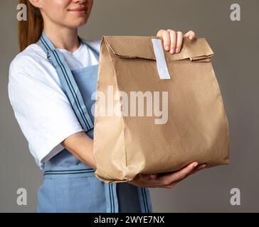 Braune recycelbare Papiertüte zum Mitnehmen in den Händen der Kellnerin. Stockfoto