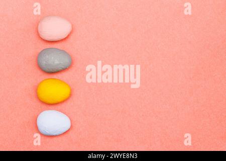 Rosa, Grau, Gelb, hellblaue dekorative Eier auf rosafarbenem Papierhintergrund. Osterkonzept aus handbemalten Eiern. Stockfoto