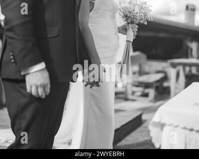 Bräutigam und Braut halten an ihrem Hochzeitstag Hände vor dem ersten Kuss, Schwarzweißfoto Stockfoto