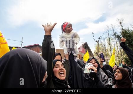 Srinagar, Indien. April 2024. Eine muslimische Frau hält ihr Kind über der Menge, während sie während eines Protests gegen Israels Militäroperationen in Gaza Slogans gegen Israel und Amerika singt. Dutzende Kaschmirmuslime trugen Plakate und palästinensische Flaggen während einer Kundgebung im zentralen Kaschmir-Magam, etwa 25 km von Srinagar entfernt, zum Gedenken an den Al-Quds-Tag (Jerusalem). Der Al-Quds-Tag wird weltweit am letzten Freitag (Jumat-ul-Vida) des Heiligen Monats Ramadan begangen, um Solidarität und Unterstützung für die Palästinenser zum Ausdruck zu bringen. Quelle: SOPA Images Limited/Alamy Live News Stockfoto