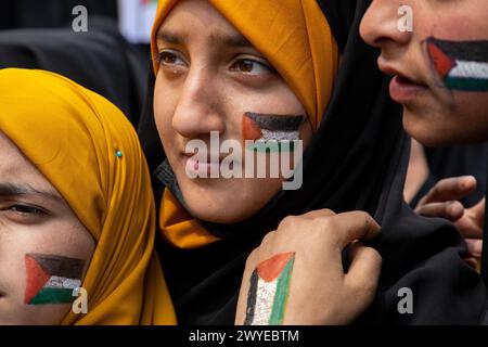 Srinagar, Indien. April 2024. Muslimische Frauen, die während eines Protests gegen Israels Militäroperationen in Gaza mit palästinensischen Fahnen auf die Wangen gemalt wurden. Dutzende Kaschmirmuslime trugen Plakate und palästinensische Flaggen während einer Kundgebung im zentralen Kaschmir-Magam, etwa 25 km von Srinagar entfernt, zum Gedenken an den Al-Quds-Tag (Jerusalem). Der Al-Quds-Tag wird weltweit am letzten Freitag (Jumat-ul-Vida) des Heiligen Monats Ramadan begangen, um Solidarität und Unterstützung für die Palästinenser zum Ausdruck zu bringen. Quelle: SOPA Images Limited/Alamy Live News Stockfoto